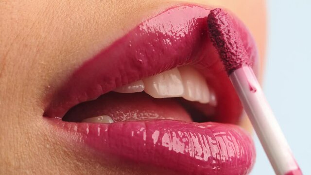 Closeup shot stylist applies lipstick  to the lips of the female model. Woman making make up applying lipstick on a lip. Professional makeup. Tutorial makeup master class. Making mua. Slow motion.