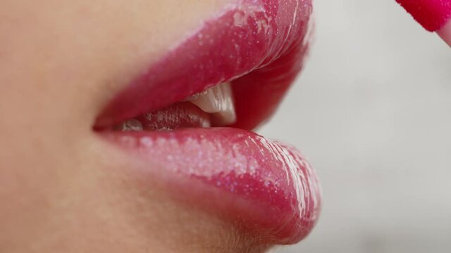 Closeup shot stylist applies lipstick  to the lips of the female model. Woman making make up applying lipstick on a lip. Professional makeup. Tutorial makeup master class. Making mua. Slow motion.