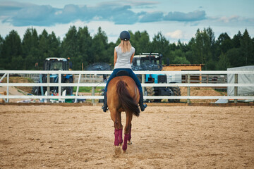 woman rider rides a horse at the ranch. back view