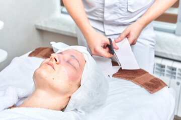 Obraz na płótnie Canvas doctor cosmetologist prepares collagen face mask for female patient