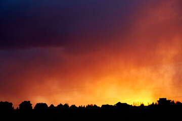 Beautiful fiery red sunset. Evening landscape. Village and forest fire silhouette. Cloudy weather....