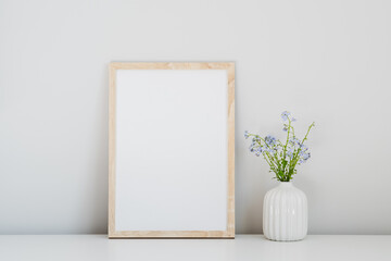 Wooden poster frame mockup and vase with fresh flowers in home interior. Minimal, Scandinavian style. Still life.
