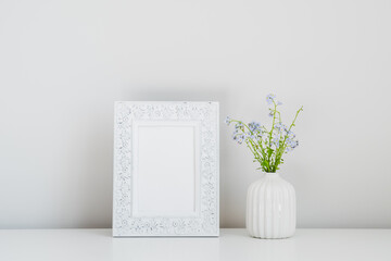 Photo frame mockup and vase with fresh flowers in home interior. Minimal, Scandinavian style. Still life.