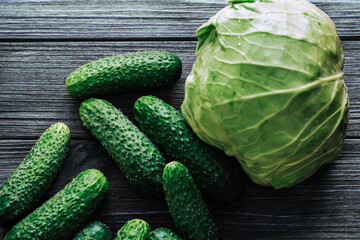 Cabbage with cucumbers top view on a background of wooden boards.