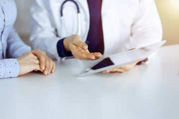 Unknown woman-doctor is showing to her patient a description of medication, while sitting together...