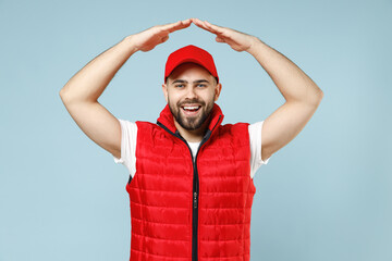 Delivery guy employee man in red cap white T-shirt vest uniform workwear work as dealer courier hold folded hands above head isolated on pastel blue color background studio portrait. Service concept.