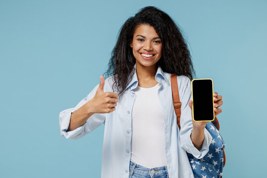 Young African American Girl Teen Student In Denim Clothes Backpack Hold Mobile Phone Blank Screen Workspace Area Show Thumb Up Isolated On Blue Background Education In High School University Concept.