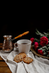 turk with coffee, black coffee cup, red flowers, cookies, lemon, wooden table, black background