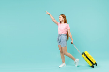 Full length traveler tourist kid girl 12-13 years old in pink t-shirt hold suitcase catch taxi isolated on pastel blue background Passenger travel abroad weekends getaway Air flight journey concept.