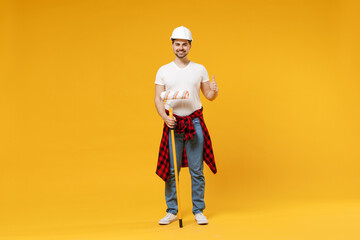 Full length young employee handyman man in protective helmet hold paint roller show thumb up gesture isolated on yellow background Instrument accessory renovation apartment room Repair home concept