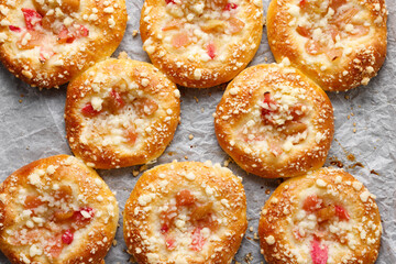 Yeast sweet buns with rhubarb and crumble on baking paper top view