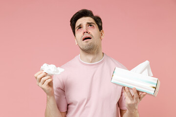 Sick unhealthy ill allergic man has red watery eyes runny stuffy sore nose suffer from allergy trigger symptom hay fever hold paper napkin handkerchief isolated on pastel pink color background studio - obrazy, fototapety, plakaty