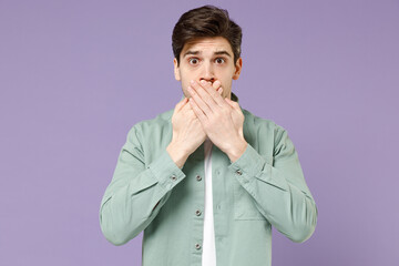 Young surprised shocked confused caucasian man 20s in casual mint shirt white t-shirt cover mouth...