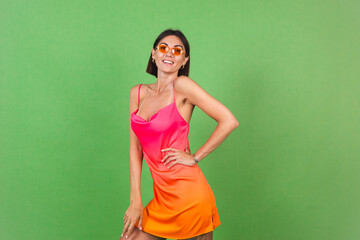 Stylish woman in pink silk dress isolated on green background posing, perfect curves, slender, tanned