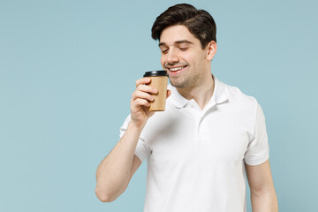 Young happy fun caucasian man 20s in white casual basic t-shirt hold takeaway delivery craft paper brown cup coffee to go isolated on pastel blue background studio portrait People lifestyle concept