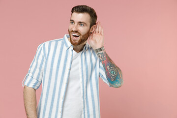 Young curious nosy caucasian unshaven man wear blue striped shirt white t-shirt try to hear you...
