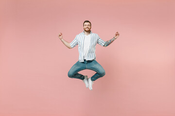 Fototapeta na wymiar Full length young unshaven man 20s wearing blue striped shirt white t-shirt jump high hold spreading hands in yoga om aum gesture relax meditate try to calm down isolated on pastel pink background