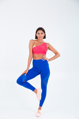 Fototapeta na wymiar Fit tanned sporty woman with abs, fitness curves, wearing top and blue leggings on white background