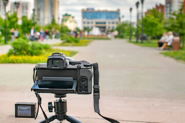 the camera and the action camera stand on the road, on the platform, on a tripod in the city park and take photos, video shooting of the city square and vacationing people