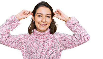 Young caucasian girl wearing wool winter sweater smiling pulling ears with fingers, funny gesture....