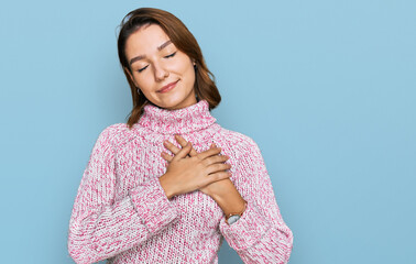 Young caucasian girl wearing wool winter sweater smiling with hands on chest with closed eyes and grateful gesture on face. health concept.