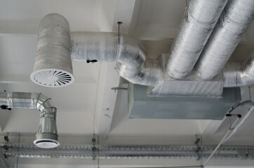 Ventilation pipes in silver insulation material hanging from the ceiling inside new building....