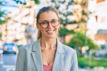 Young blonde businesswoman smiling happy standing at the city.