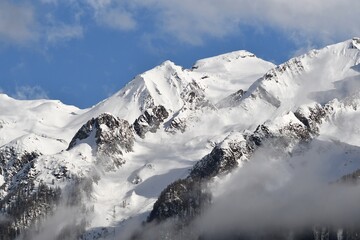 Ośnieżone alpejskie szczyty pośród mgieł.
