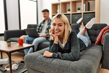 Young caucasian couple smiling happy using laptop sitting on the sofa at home.