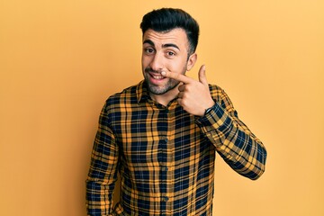 Young hispanic man wearing casual clothes pointing with hand finger to face and nose, smiling cheerful. beauty concept