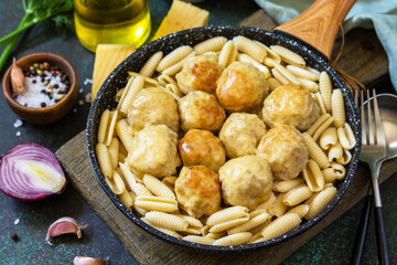 Italian pasta. Spaghetti with meatballs in cheese sauce on a dark  stone or concrete background.