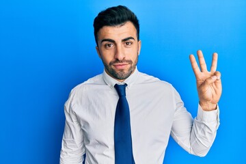 Young hispanic man wearing business clothes showing and pointing up with fingers number three while smiling confident and happy.