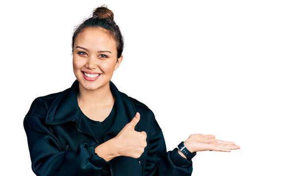 Young hispanic girl wearing sportswear showing palm hand and doing ok gesture with thumbs up, smiling happy and cheerful
