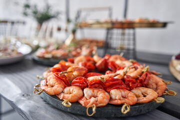 Delicious fresh seafood, shrimp with fresh vegetables. buffet table with lots of delicious snacks. canapes, bruschetta, and little desserts on wooden plate board