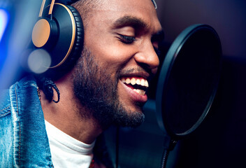 Bearded afro american man singing to microphone recording song in music studio production - Music,...
