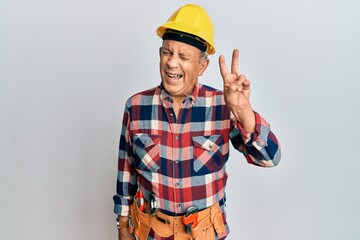 Senior hispanic man wearing handyman uniform smiling with happy face winking at the camera doing...