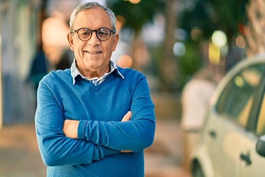Senior grey-haired man with arms crossed smiling happy standing at the city.