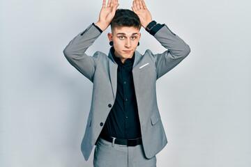 Young caucasian boy with ears dilation wearing business jacket doing bunny ears gesture with hands palms looking cynical and skeptical. easter rabbit concept.