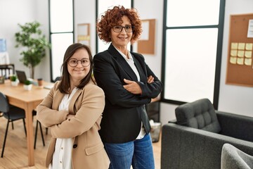 Group of two women working at the office. Mature woman and down syndrome girl working at inclusive...