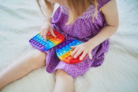 Unrecognizable little girl playing with pop it fidget