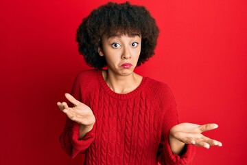 Young hispanic girl wearing casual clothes clueless and confused expression with arms and hands...
