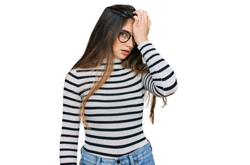 Young beautiful teen girl wearing casual clothes and glasses surprised with hand on head for mistake, remember error. forgot, bad memory concept.