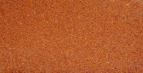 Fototapeta premium Background from the seeds of Camelina sativa. Raw materials for the manufacture of camellina oil. Oilseed crops. View of the embankment from above.