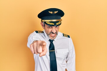 Handsome middle age man with grey hair wearing airplane pilot uniform pointing displeased and frustrated to the camera, angry and furious with you