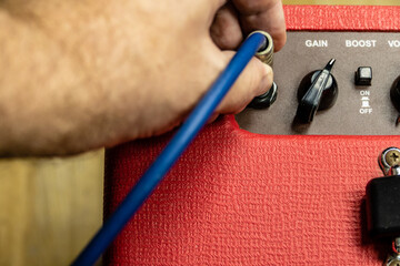 Close up of hand plugging in jack on amp