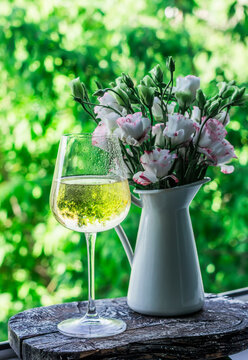 Glass of summer refreshing cocktail and a bouquet of eustom flowers on the window in the room with a view of the garden