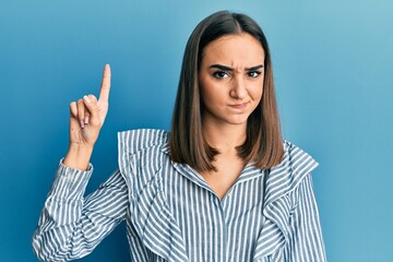 Young brunette student girl pointing up with finger skeptic and nervous, frowning upset because of problem. negative person.