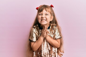 Little caucasian girl kid wearing festive sequins dress praying with hands together asking for forgiveness smiling confident.