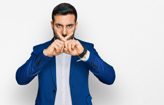 Young hispanic man wearing business jacket rejection expression crossing fingers doing negative sign