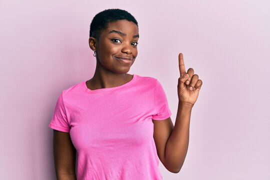 Young African American Woman Wearing Casual Pink T Shirt Smiling With An Idea Or Question Pointing Finger Up With Happy Face, Number One